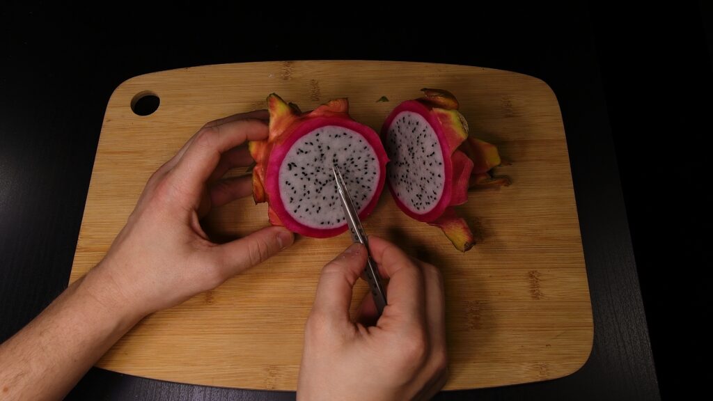 Scooping dragon fruit seeds out of the fruit