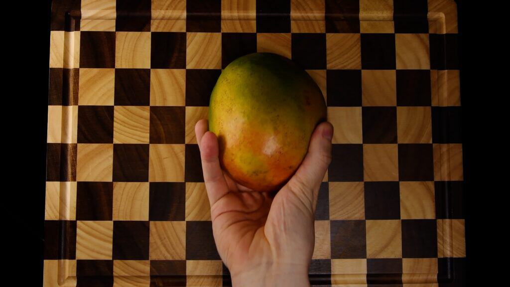 Ripe mango held in a hand before extracting the seed