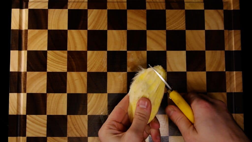 Cutting open the woody mango husk with a knife to reach the seed