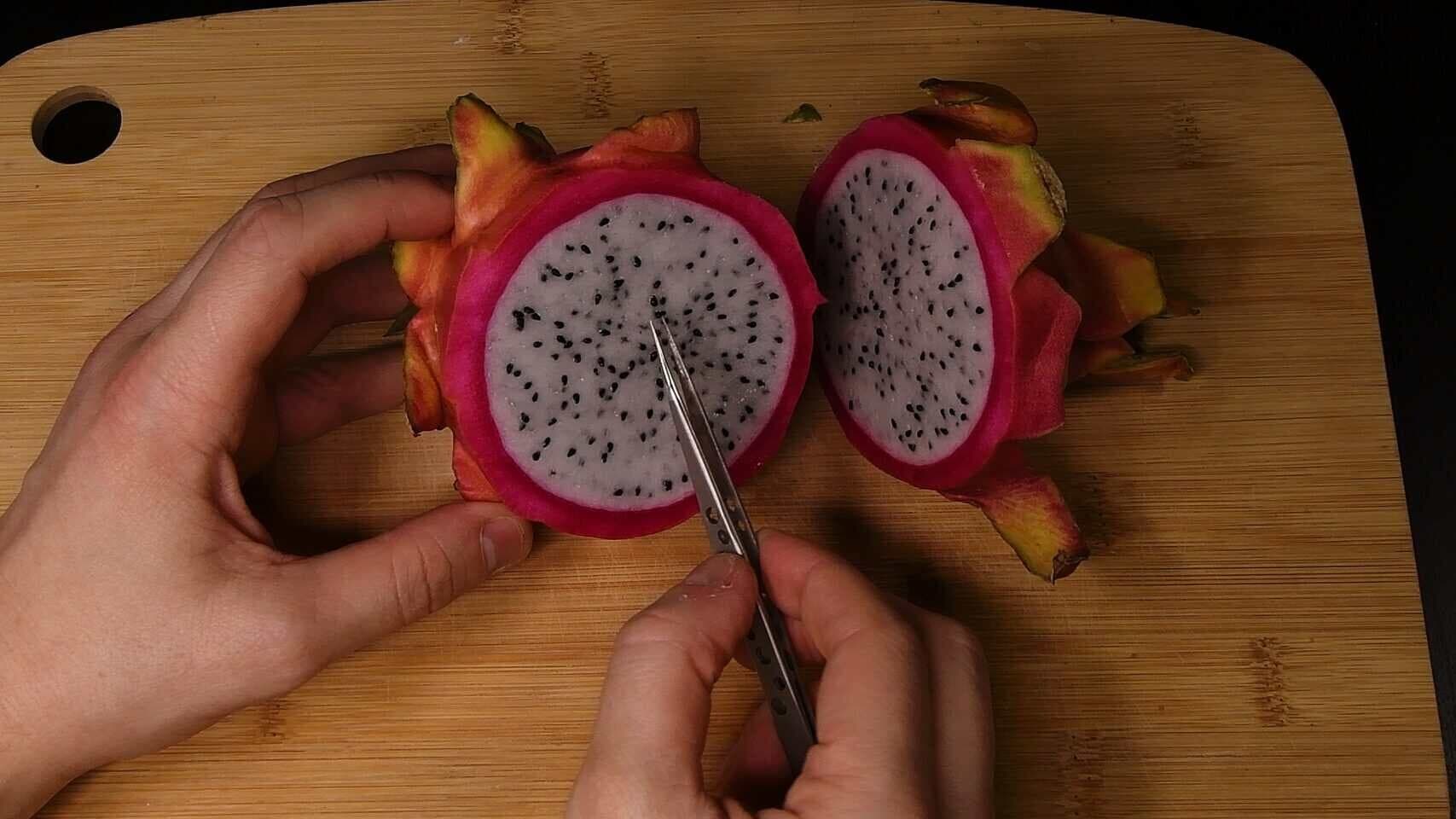 Scooping dragon fruit seeds out of the fruit
